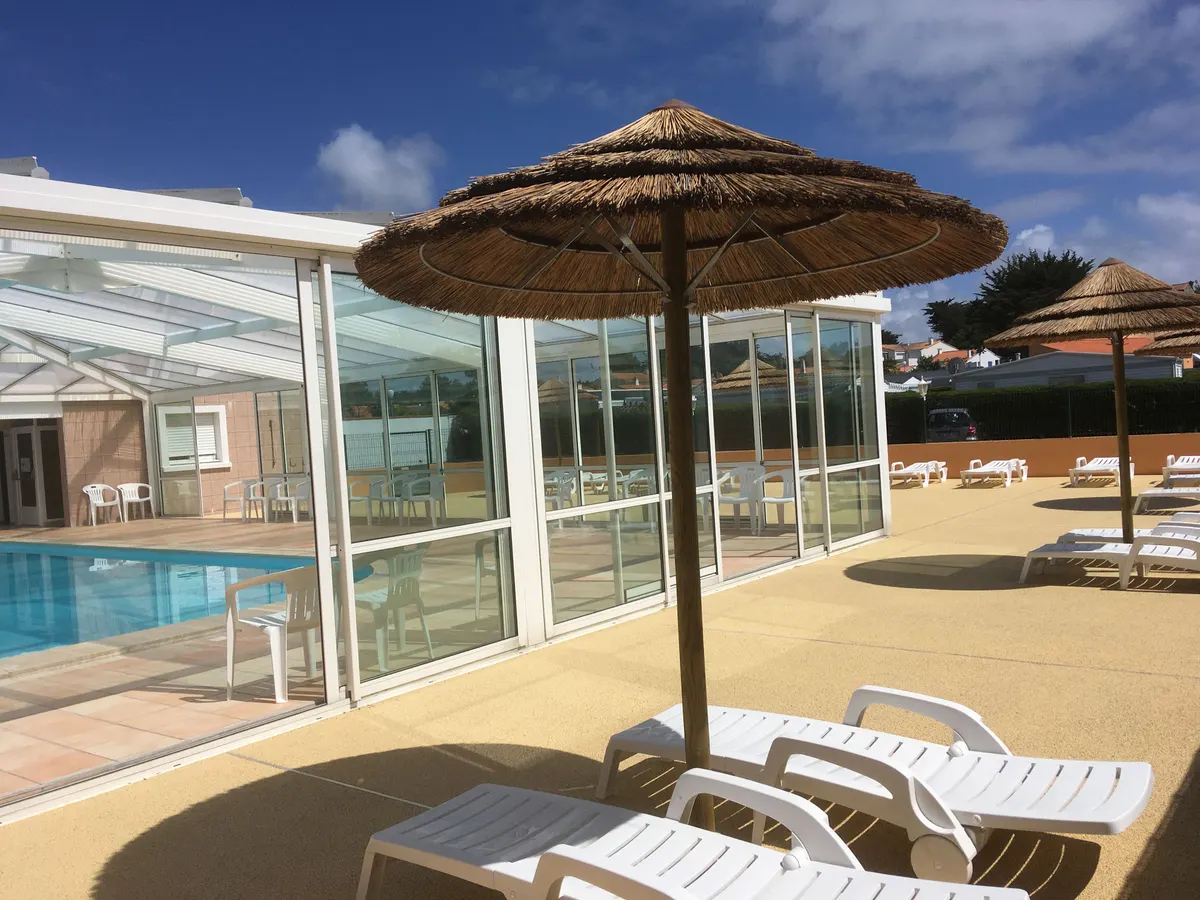 La piscine couverte et ses transats sous la véranda